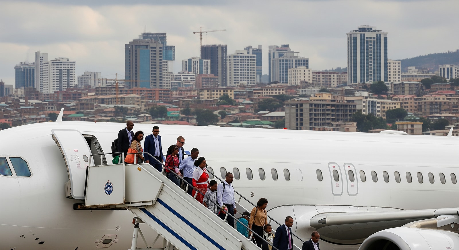 Passengers disembarking at Bole International Airport with Addis Ababa skyline in the background, showing increased international connectivity and tourism