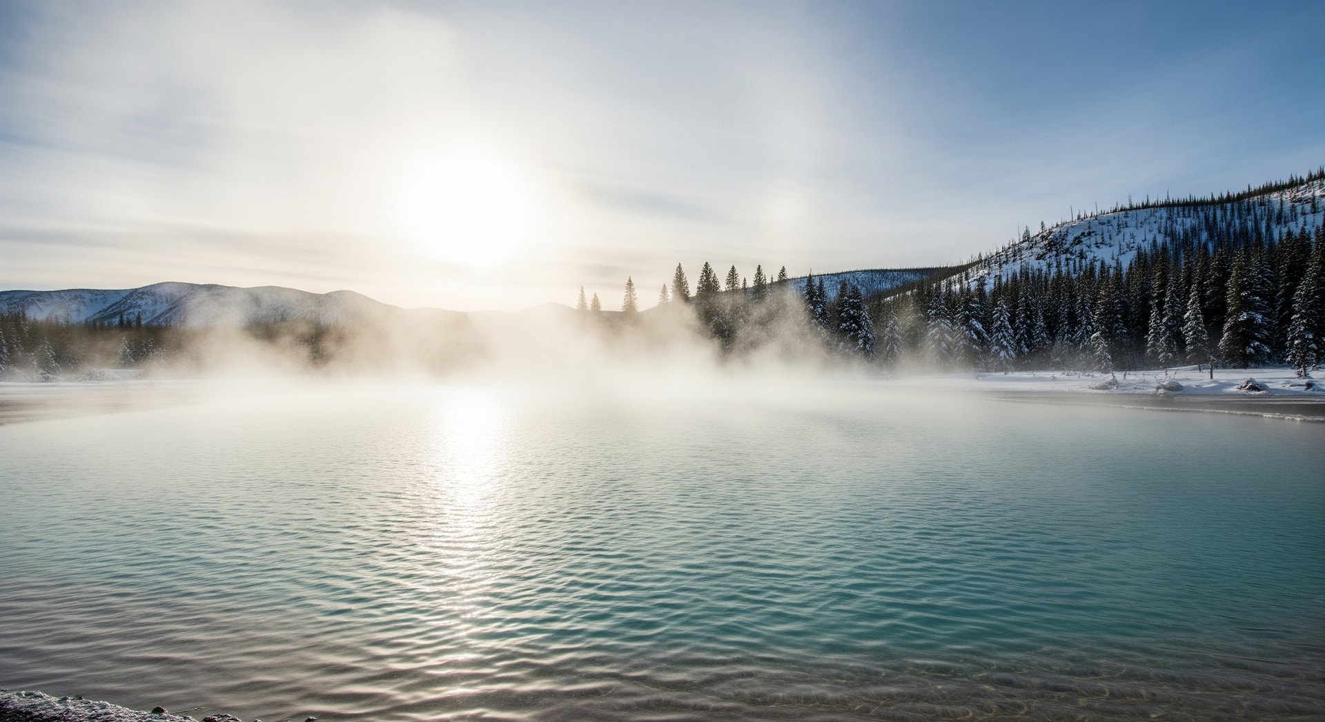 Steaming hot springs pool surrounded by snow-covered landscape